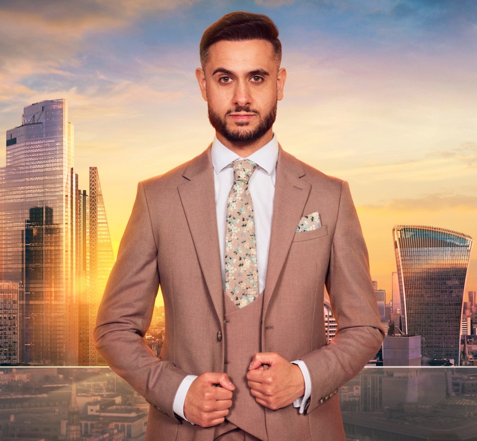 A man in a tan suit stands in front of a London cityscape at sunset.