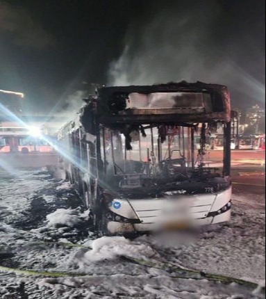 Burned-out bus covered in fire suppressant foam.
