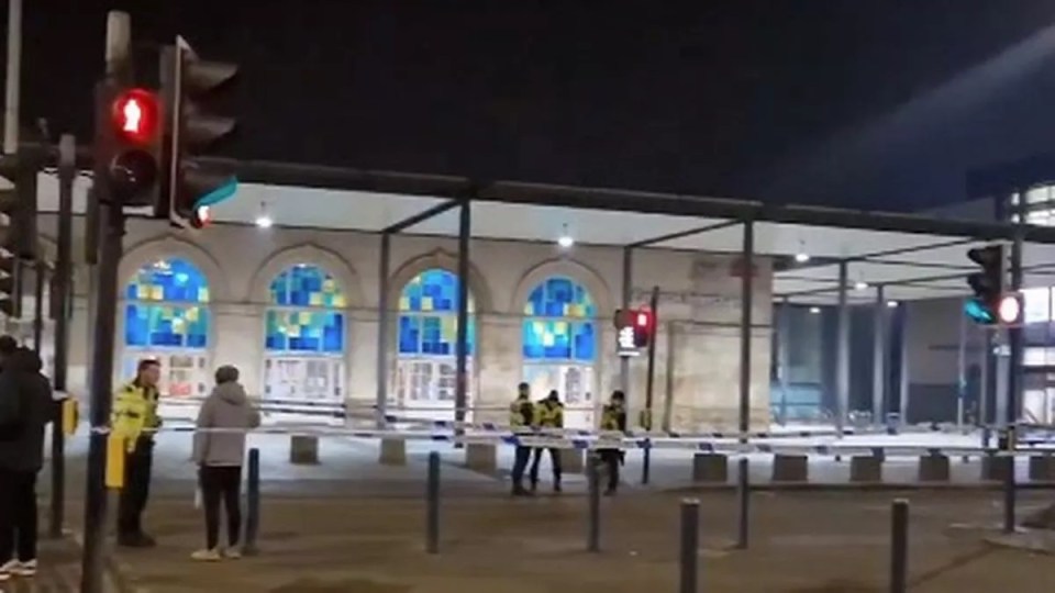 Police officers at a cordoned-off area outside a building at night.