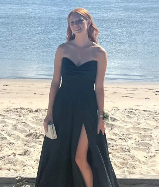 Woman in a black dress on a beach.