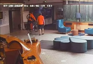 Two people with bicycles in a building lobby.