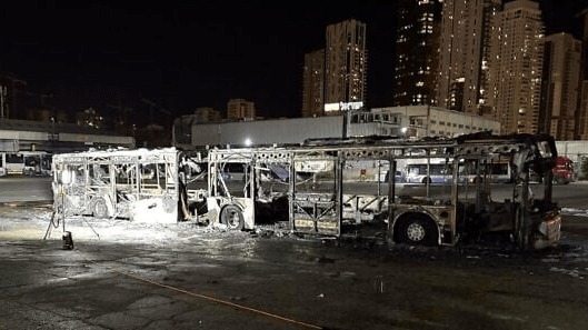 Burned-out bus at night.