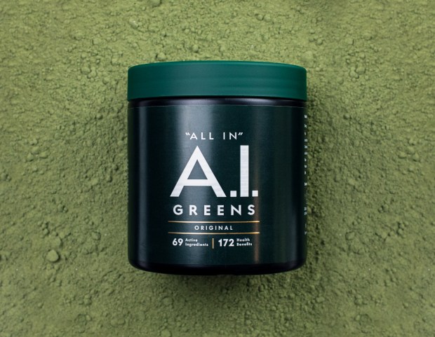 A.I. Greens Original container on a bed of green powder.