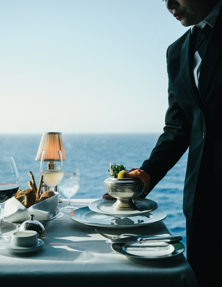 Waiter serving seafood at a table overlooking the ocean.