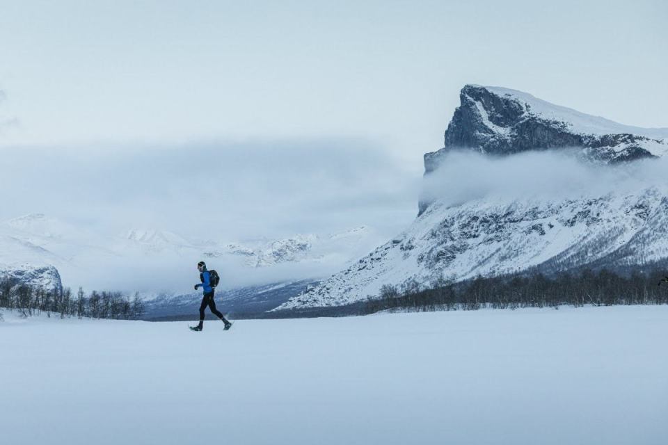 Person snowshoeing in a snowy mountainous landscape.