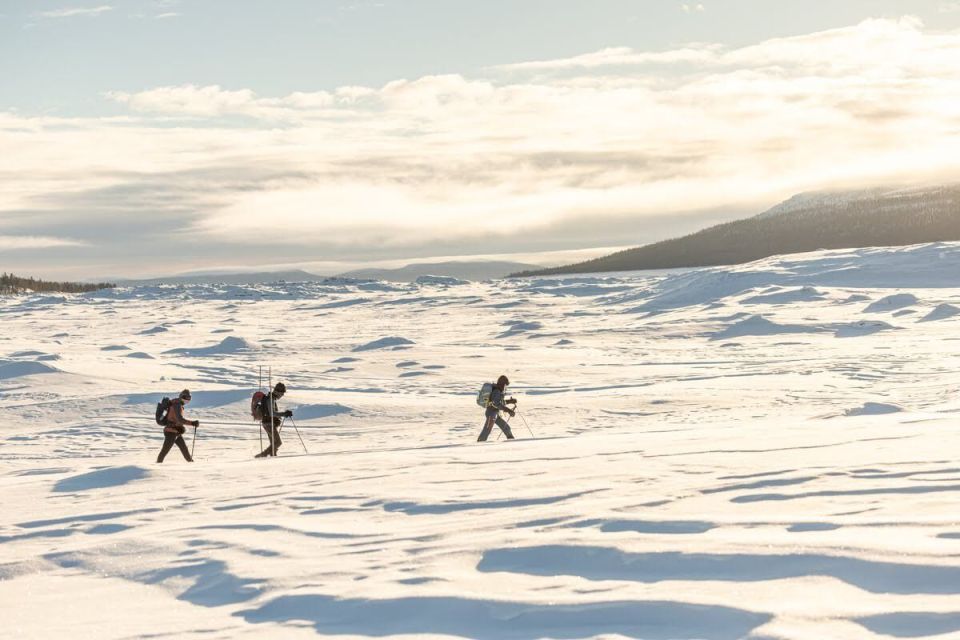 Three people ski across a snowy, flat expanse.