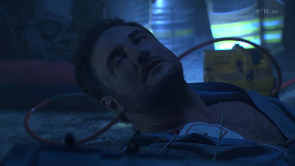 Man lying on the ground receiving medical attention.