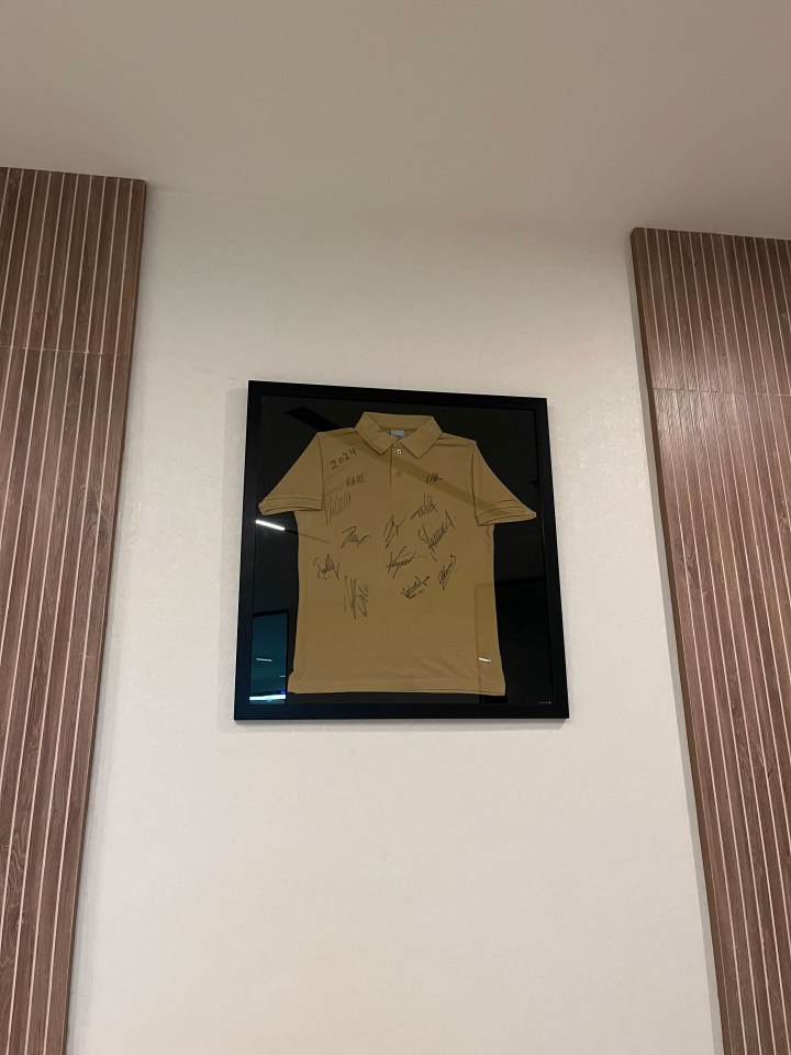 Framed tan polo shirt with multiple signatures.