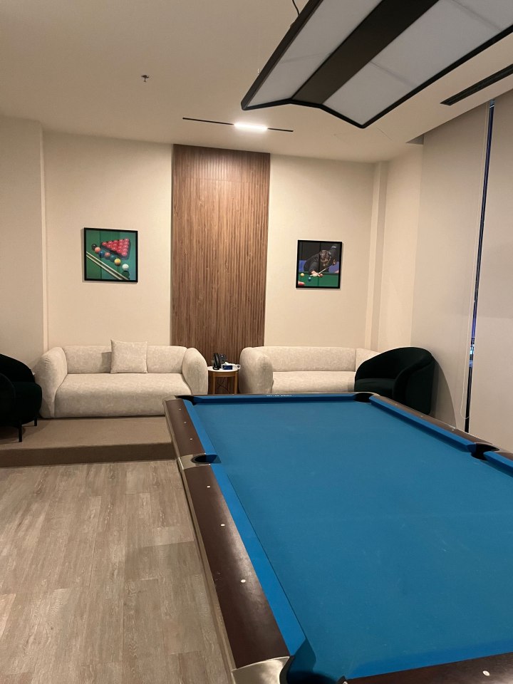 Pool table in a game room with a sofa and framed pictures.