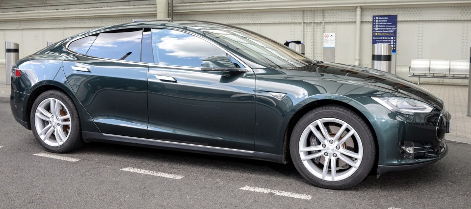 Dark green Tesla parked outside.