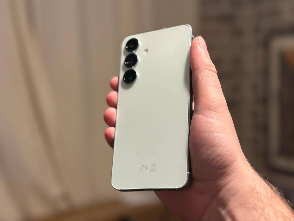 A hand holding a light green Samsung phone.