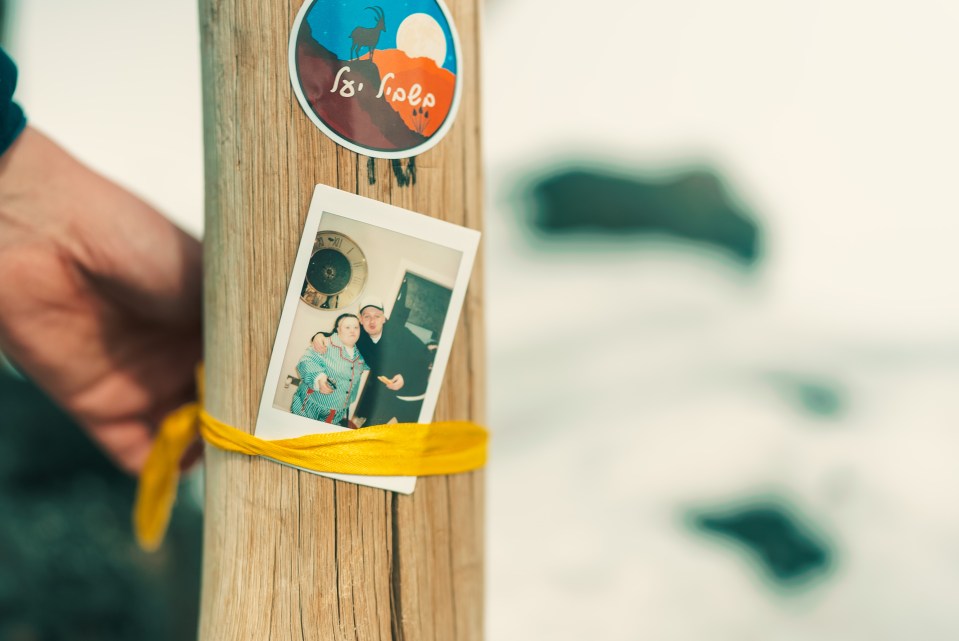 Polaroid photo tied to a wooden post with yellow ribbon.