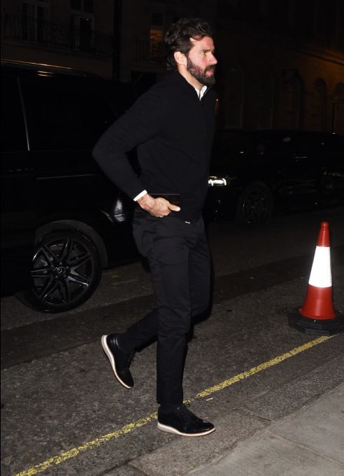 Man in black walking down a street at night.