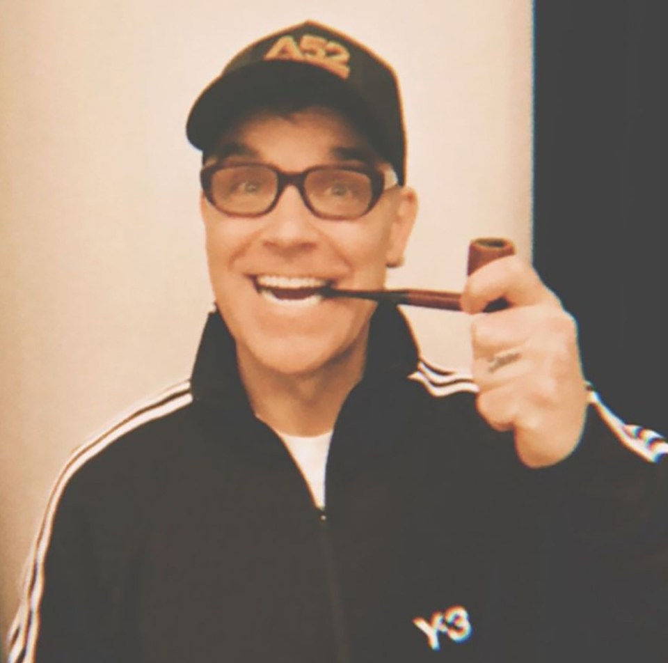 Robbie Williams holding a pipe.