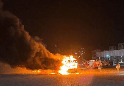 Burning bus with firefighters.