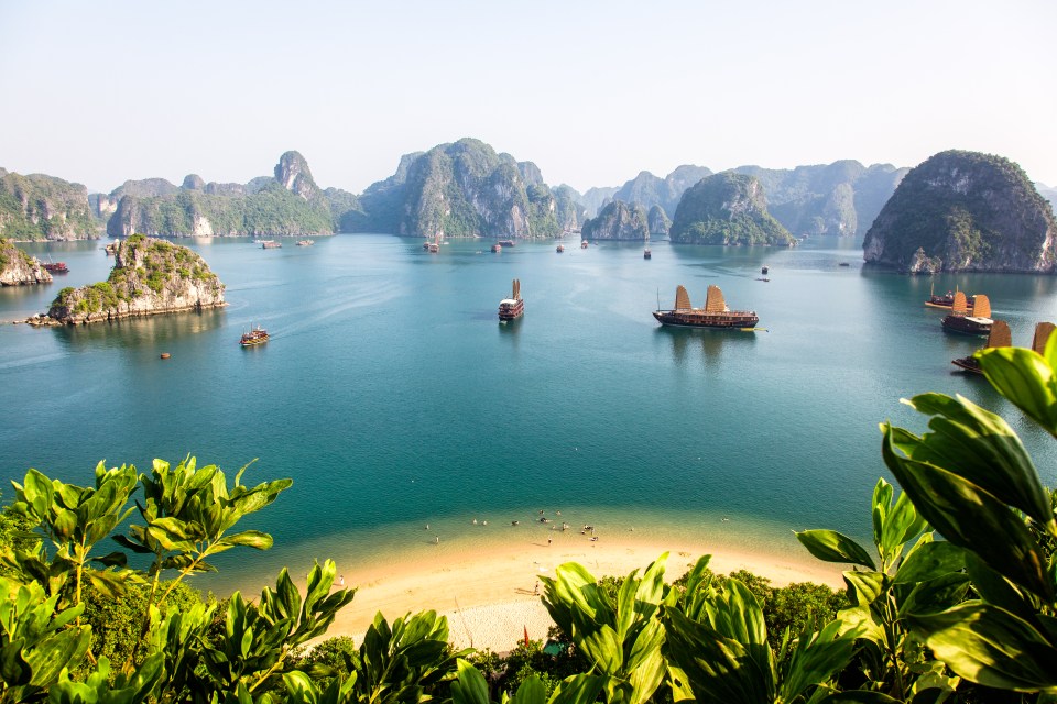 Aerial view of Halong Bay with junks and a small beach.