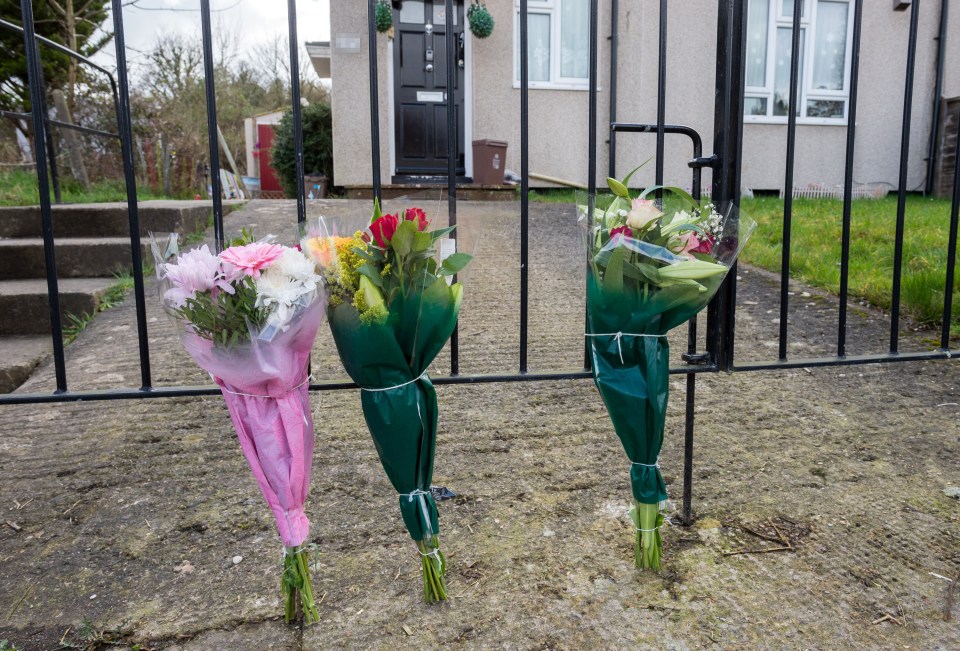 Three bouquets of flowers left at a gate.