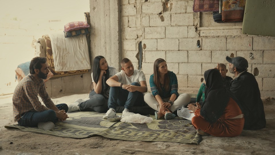 A group of people sitting on the floor and talking.
