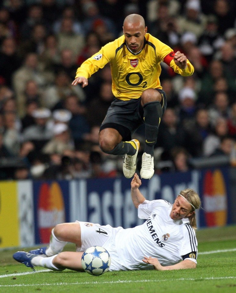 Thierry Henry of Arsenal jumping over Jose Maria Guti of Real Madrid during a soccer match.
