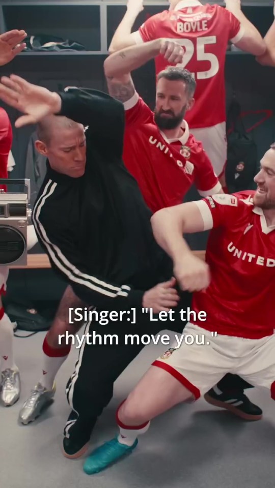 Channing Tatum dancing with Wrexham AFC soccer players in a locker room.