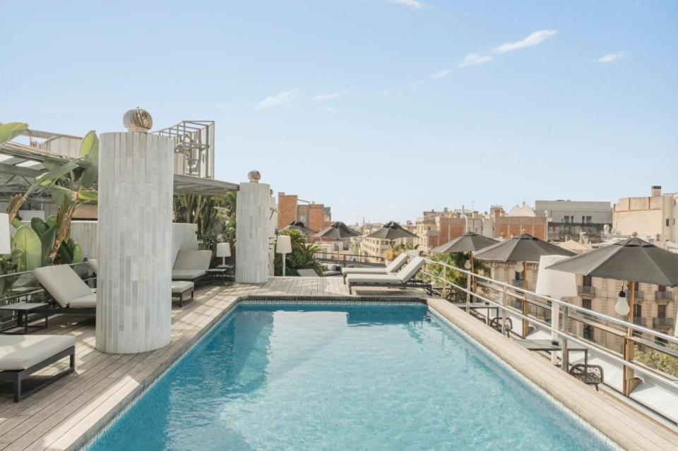 Rooftop pool and lounge area at a hotel, overlooking the city.