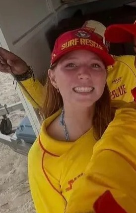 Two teenage girls in surf rescue uniforms take a selfie.