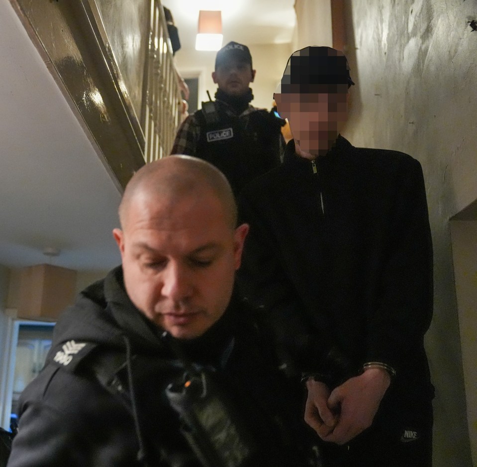 Police officers arresting a suspect in a hallway.