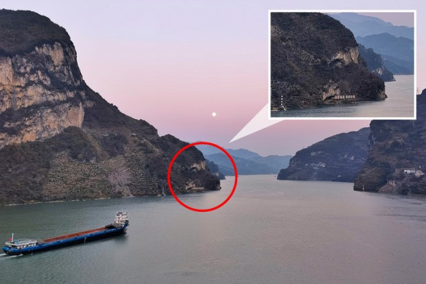 Cargo ship on a river surrounded by mountains.