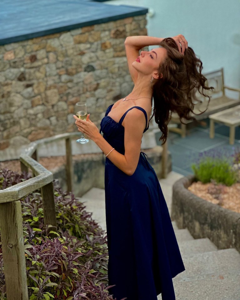 Woman in a blue dress holding a glass of champagne.