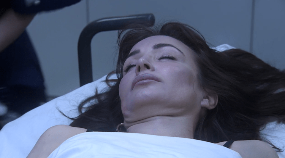 A woman lying on a hospital bed, appearing unconscious.