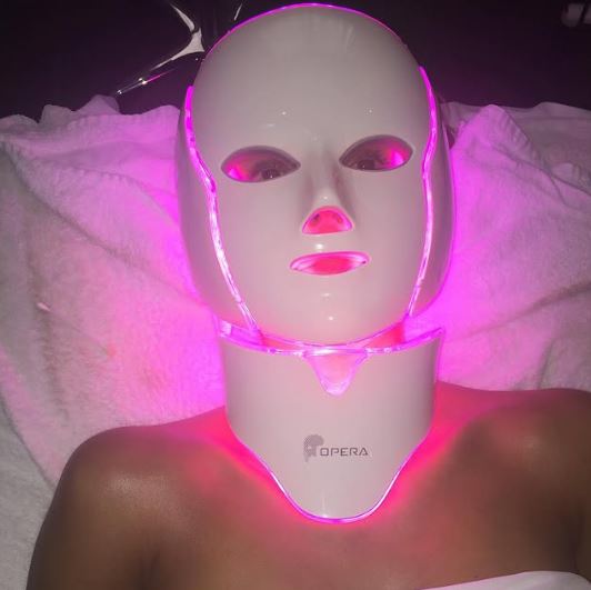 Person using a pink LED light therapy mask.