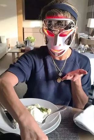 Woman wearing a red light therapy mask while eating.
