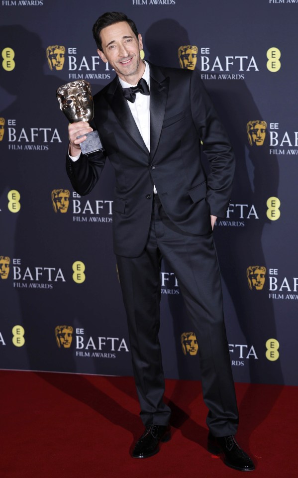 Adrian Brody holding a BAFTA award.