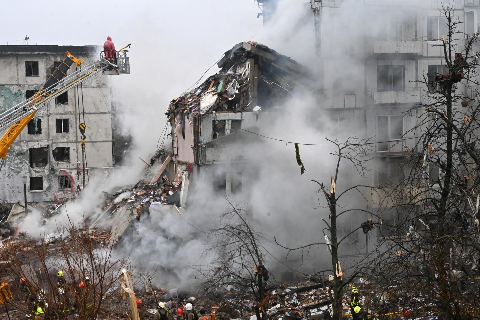Firefighter inspecting rubble of a damaged residential building after a missile strike.