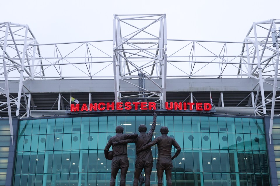 Old Trafford stadium with the Manchester United sign and the United Trinity statue.
