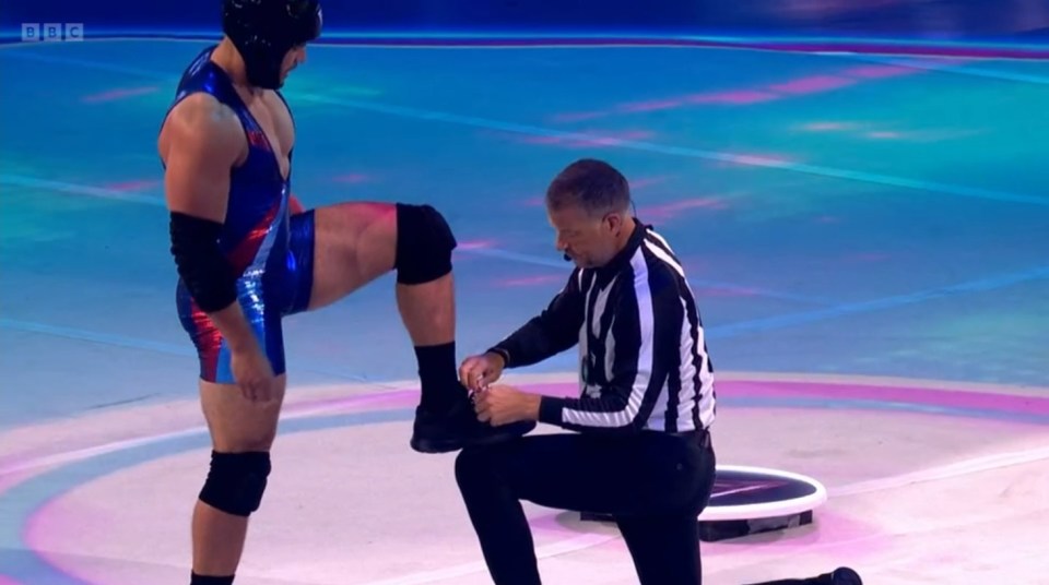 Referee tying a gladiator's shoe.