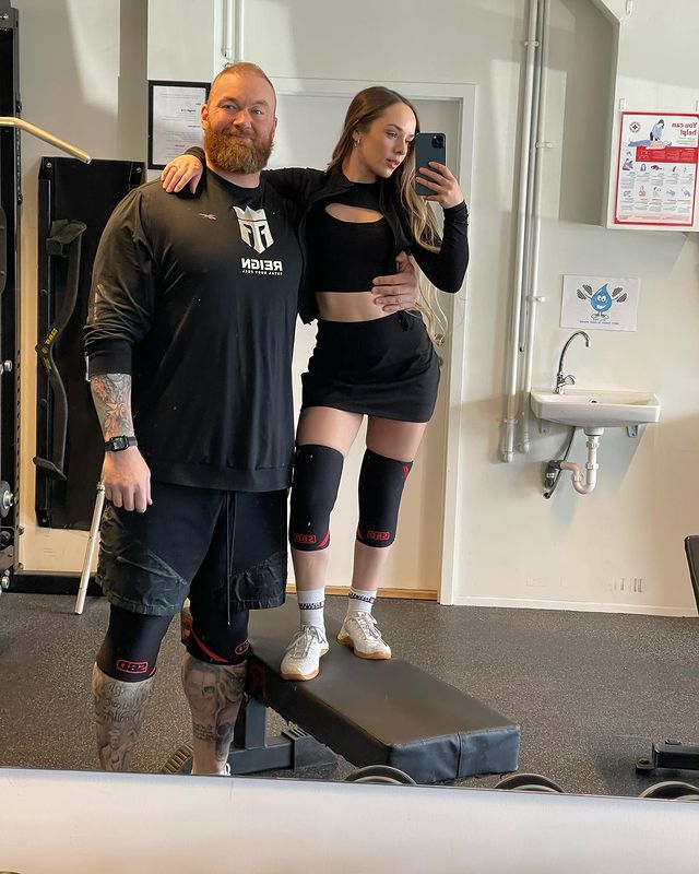 Hafþór Júlíus Björnsson and Kelsey Henson posing together in a gym.