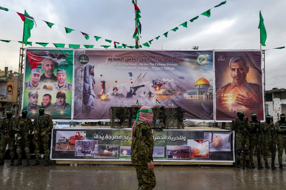 Hamas fighters in Rafah, Gaza, stand before a large banner depicting military actions and leaders.