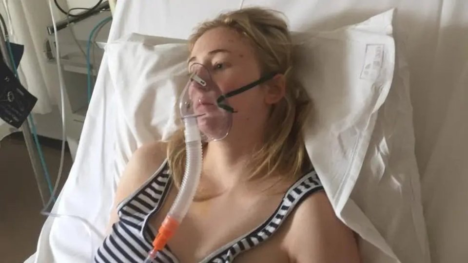 Woman in hospital bed wearing oxygen mask.