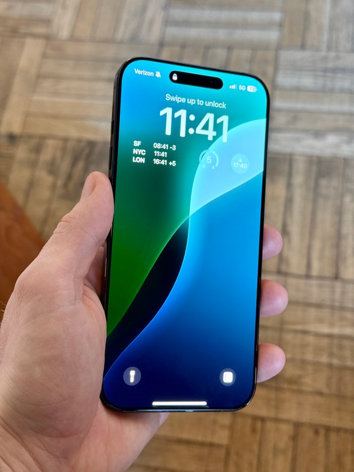 Hand holding iPhone showing lock screen.