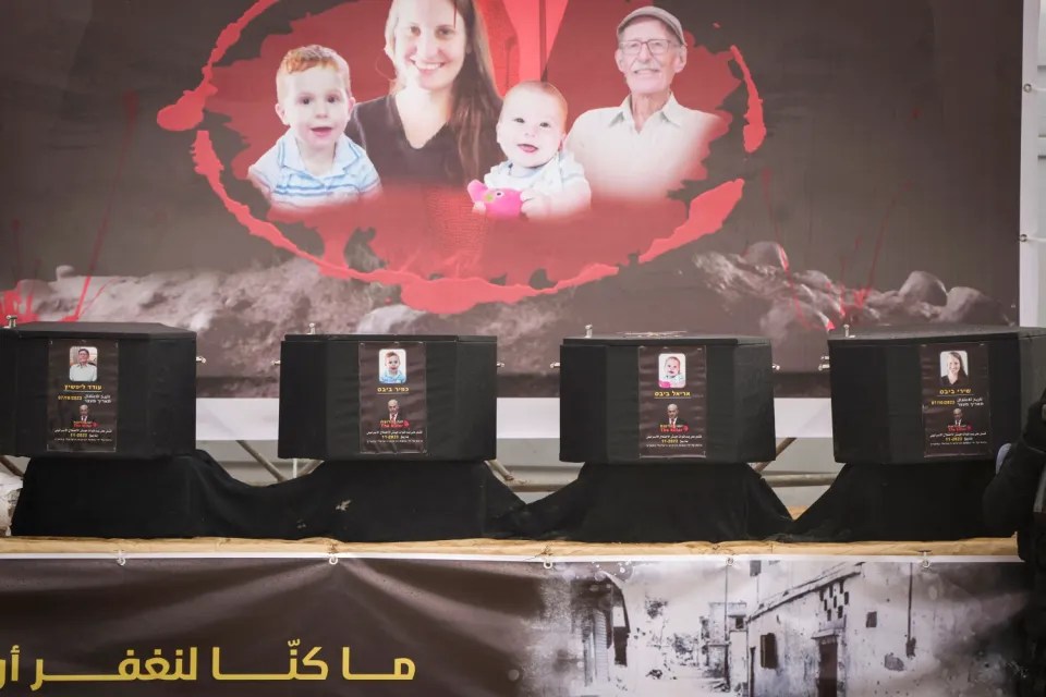 Four caskets with photos of victims and their families displayed in front of a backdrop showing additional family photos.