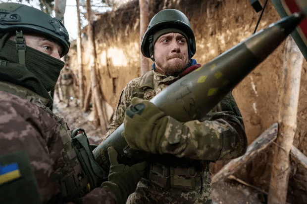 Two soldiers carrying a large missile.