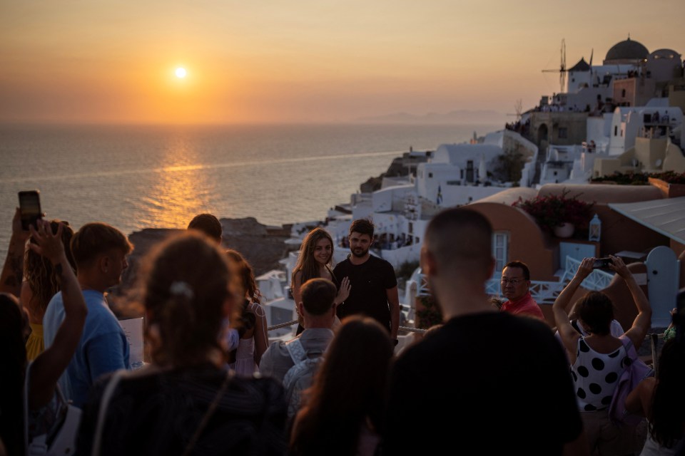 Couple posing at sunset overlooking a Greek village.