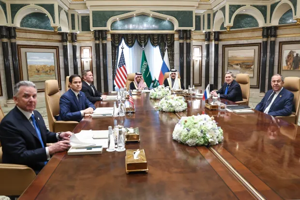 Group of men sitting at a long conference table.