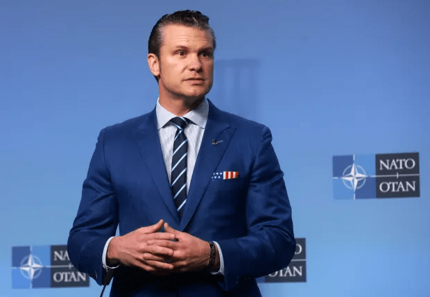 Man in blue suit speaking at NATO press conference.