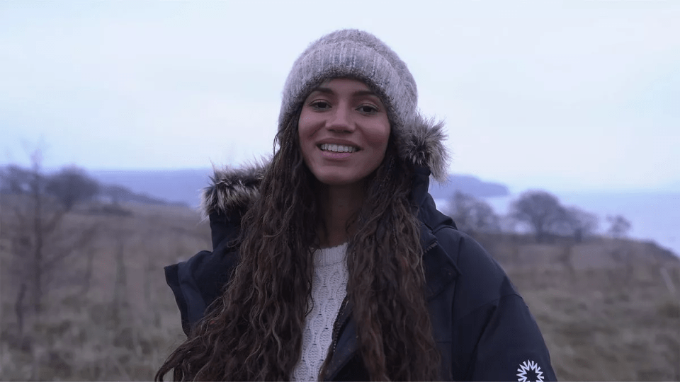 Woman in winter hat and coat smiling outdoors.