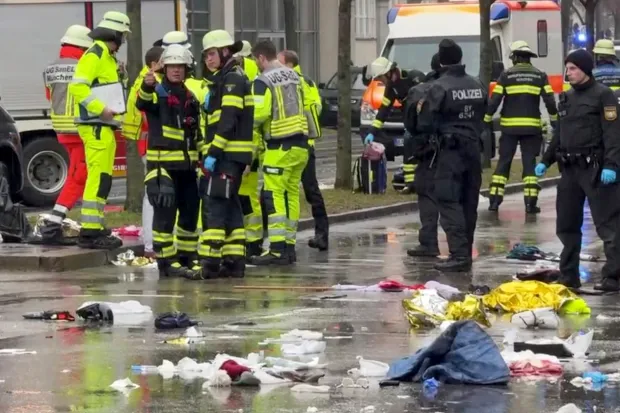 Emergency personnel and debris in a wet street.
