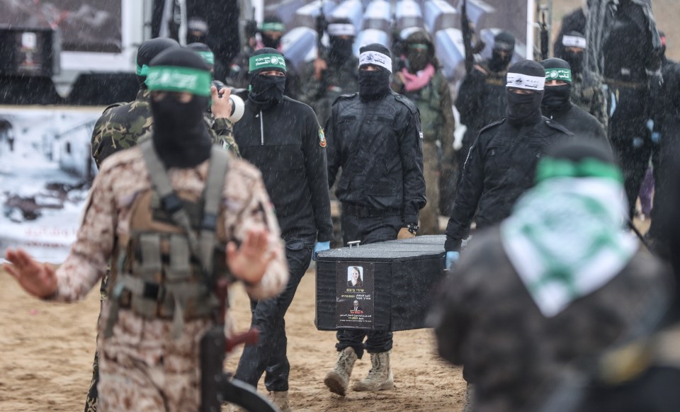 Men in military uniforms carry a coffin.