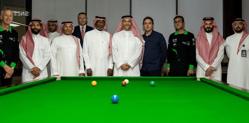 Group of men standing behind a snooker table.