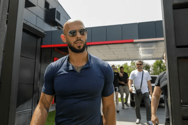 A bald man with a beard and sunglasses walks toward the camera.